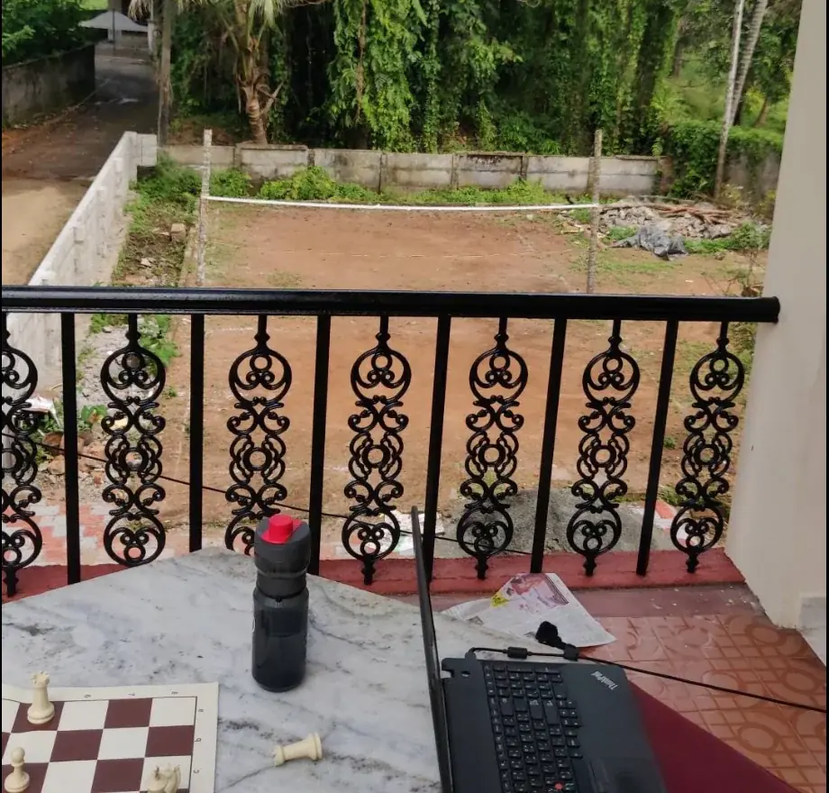 My internship desk at Community Valley, Kochi: a laptop on a marble table by the balcony, with a chessboard beside it
