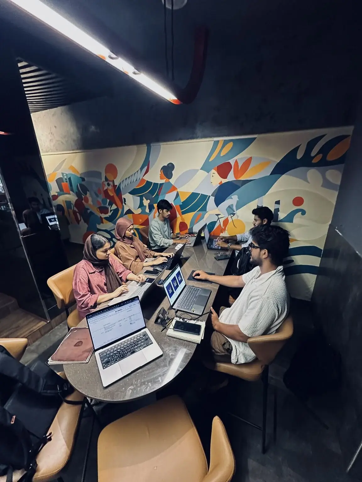 The team at work on laptops around a table at HW Growth Studio
